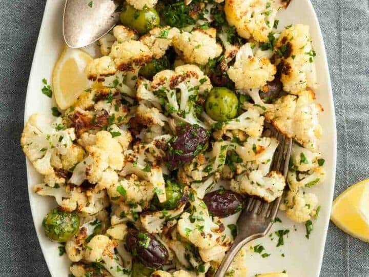 Roasted Cauliflower with Olives on Platter with Lemon Wedges