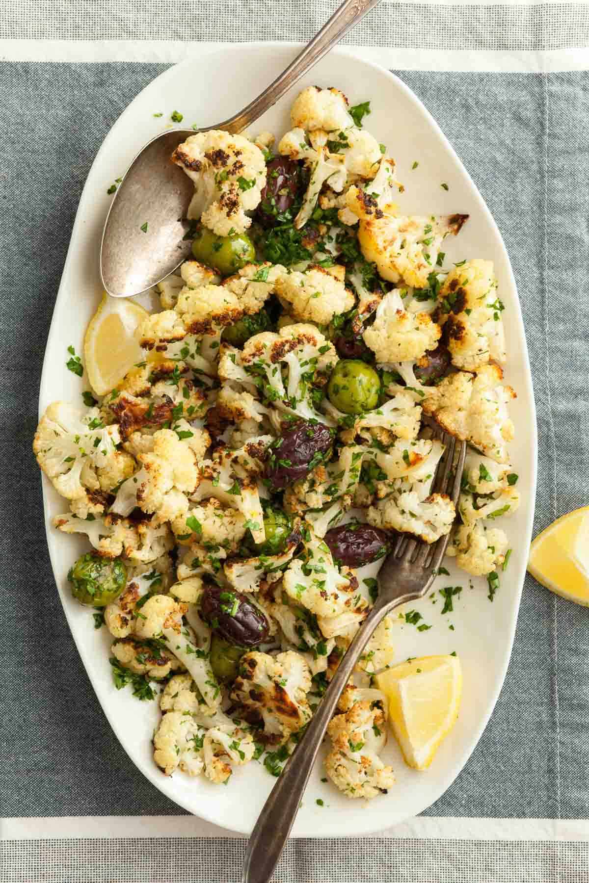 Roasted Cauliflower with Olives on Plate with Lemon Wedges