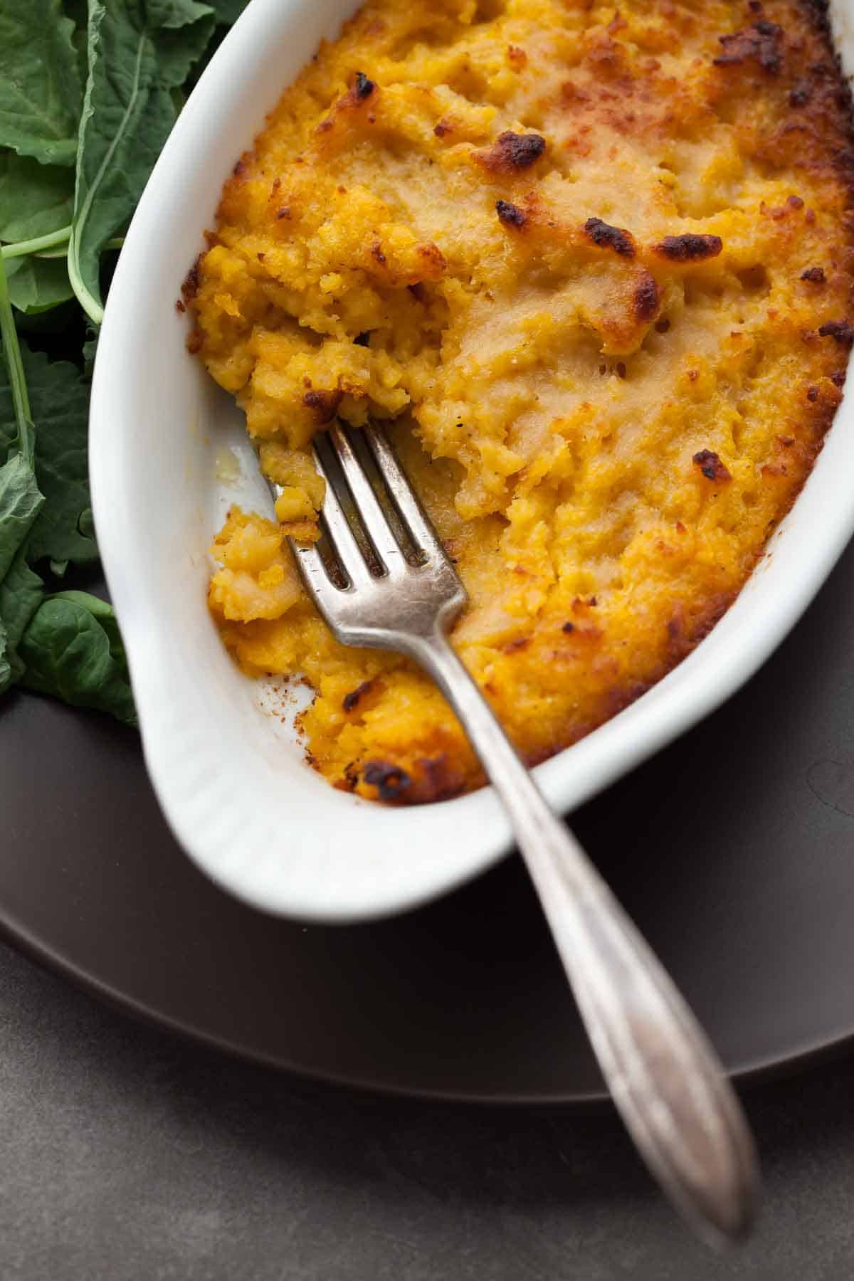Twice Baked Roasted Butternut Squash Gratin with Parmesan and Sage in Baking Dish with Fork