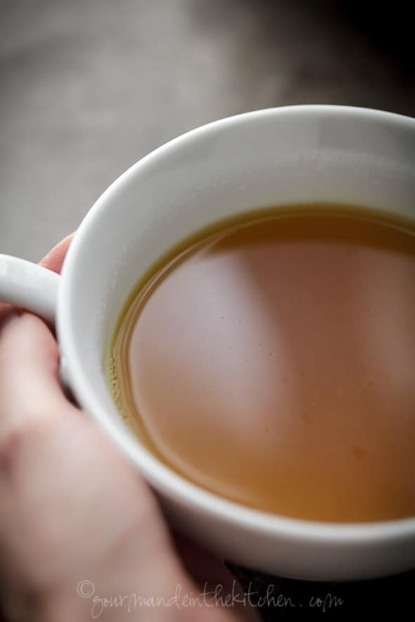 Spiced Persimmon, Ginger, Cinnamon, Turmeric Tea in cup with hands around it