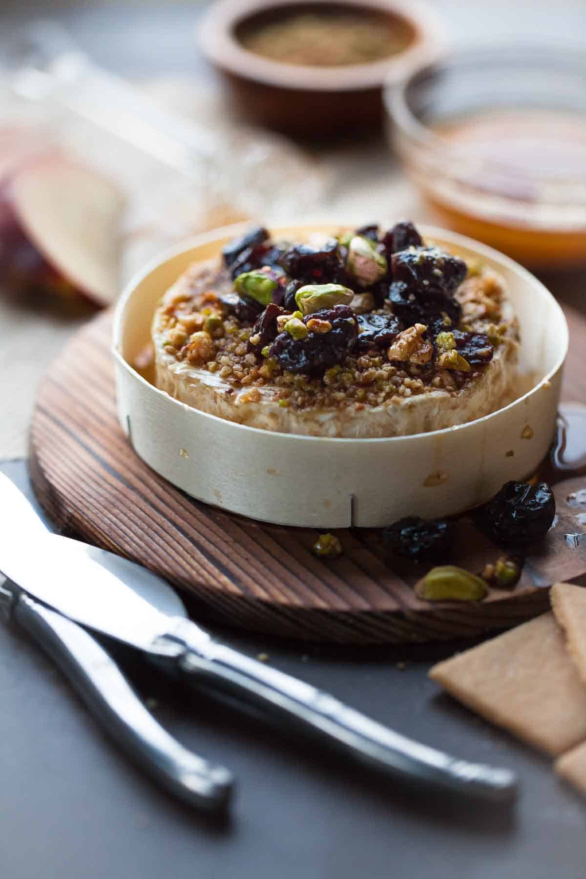 Baked brie is crusted in Dukkah then topped with chopped nuts and dried fruit.