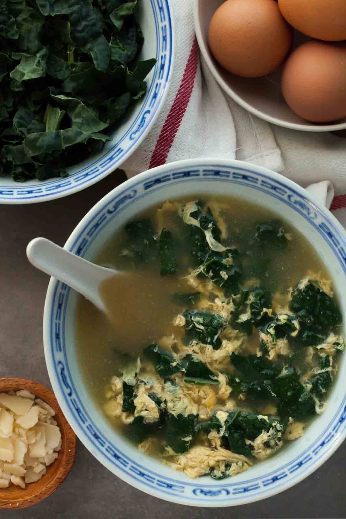 Stracciatella alla Romana in Bowl with Bowls of Greens and Eggs