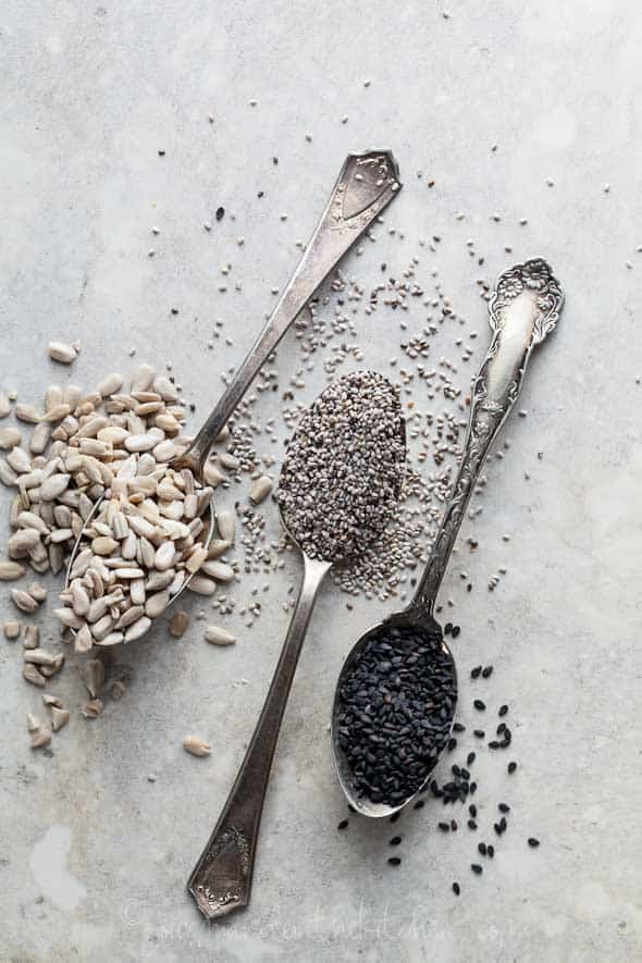 chia seeds, sunflower seeds, black sesame seeds in spoons