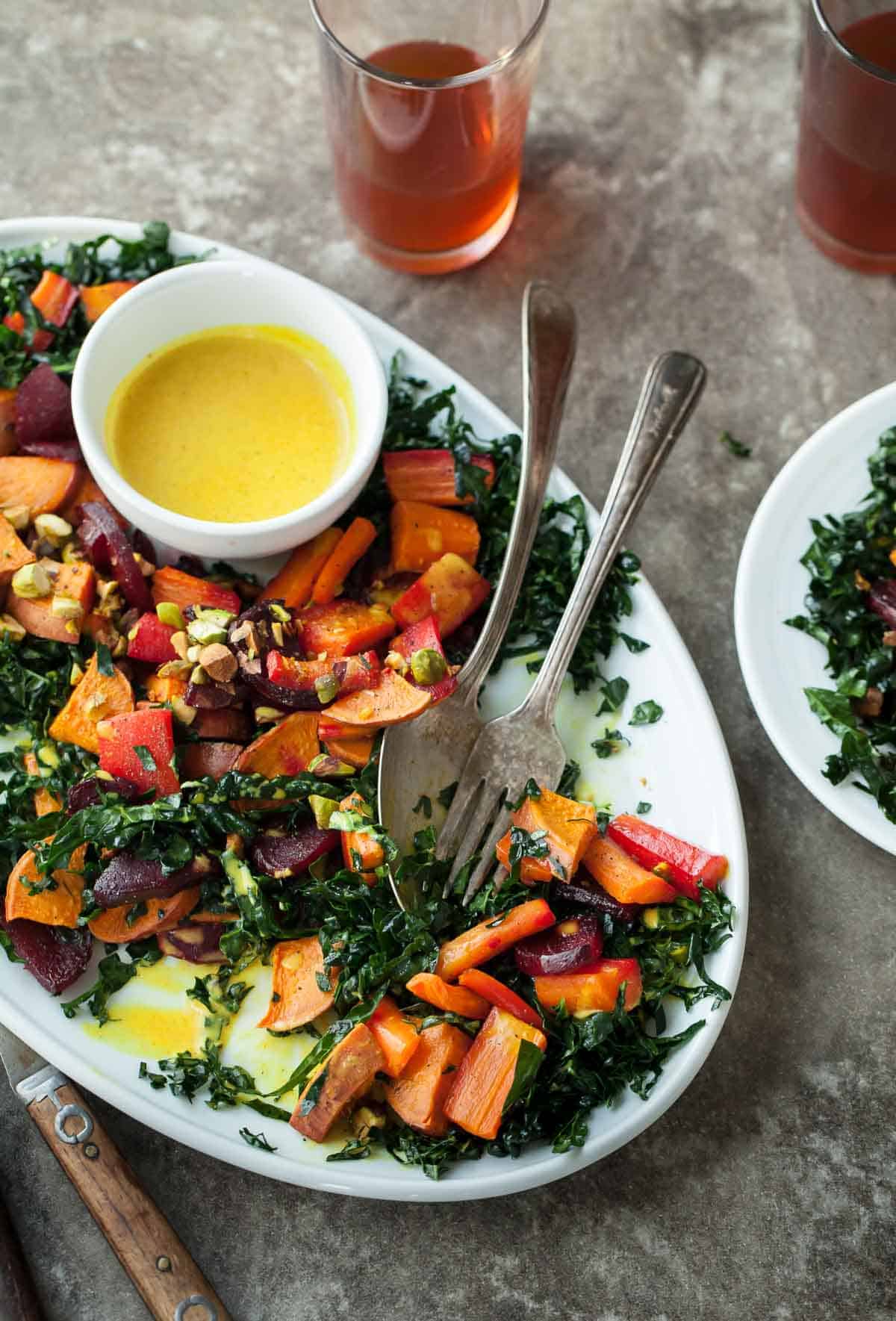 Roasted Root Vegetable and Kale Salad with Creamy Turmeric Dressing on Serving Plate with Spoon and Fork