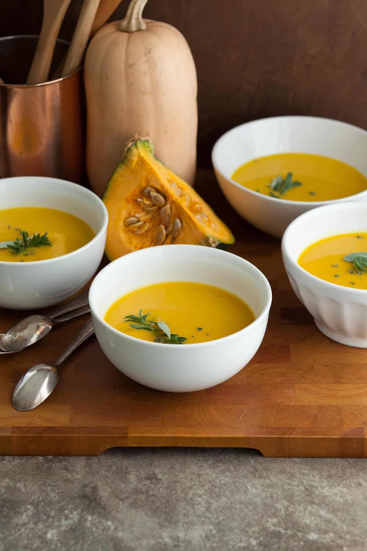 Winter Squash Soup in White Bowls with Herb Garnish