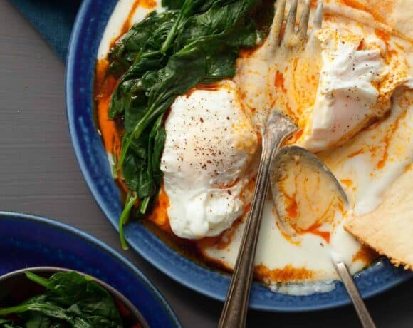 Turkish Poached Eggs (Çılbır) on plate with fork and spoon