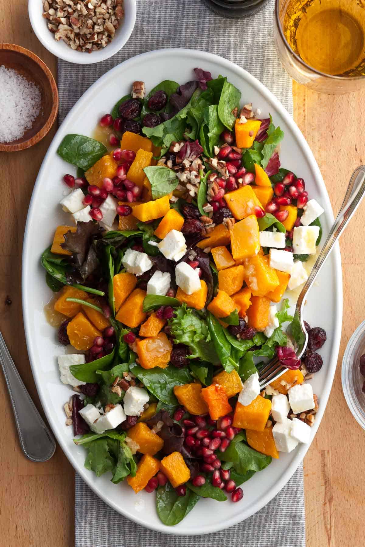 Roasted butternut squash salad with feta, cranberries, and pomegranate on a white plate