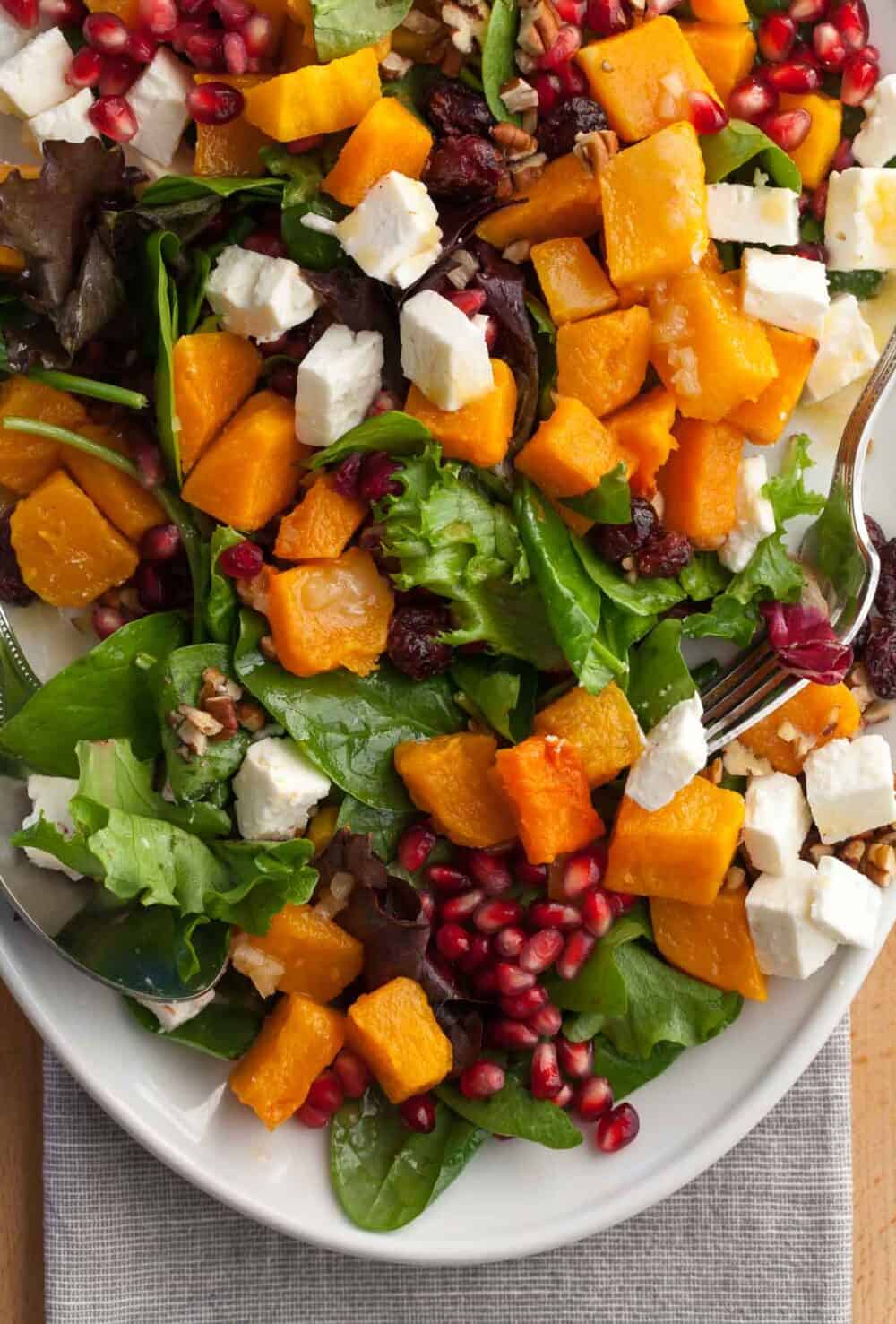 Colorful fall salad with roasted squash, baby greens, pecans, and maple Dijon dressing.”