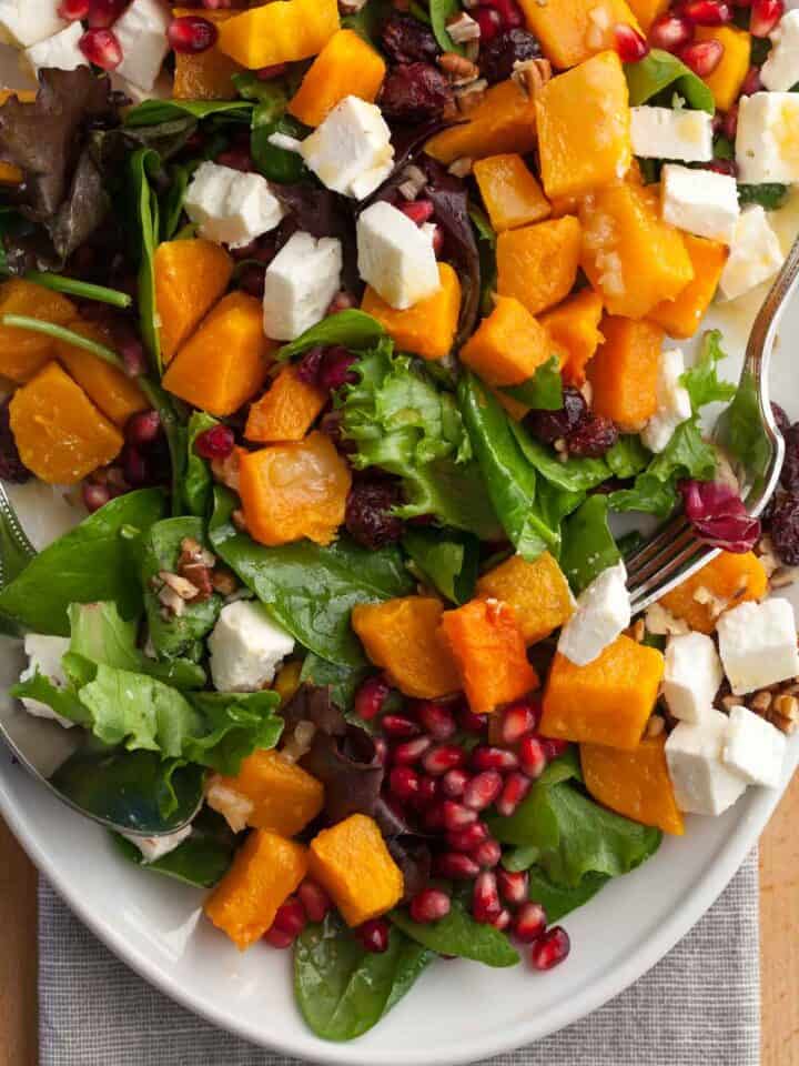 Colorful fall salad with roasted squash, baby greens, pecans, and maple Dijon dressing.”