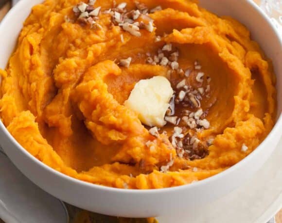 Steamed sweet potatoes mashed with vegan butter & maple syrup in serving bowl.