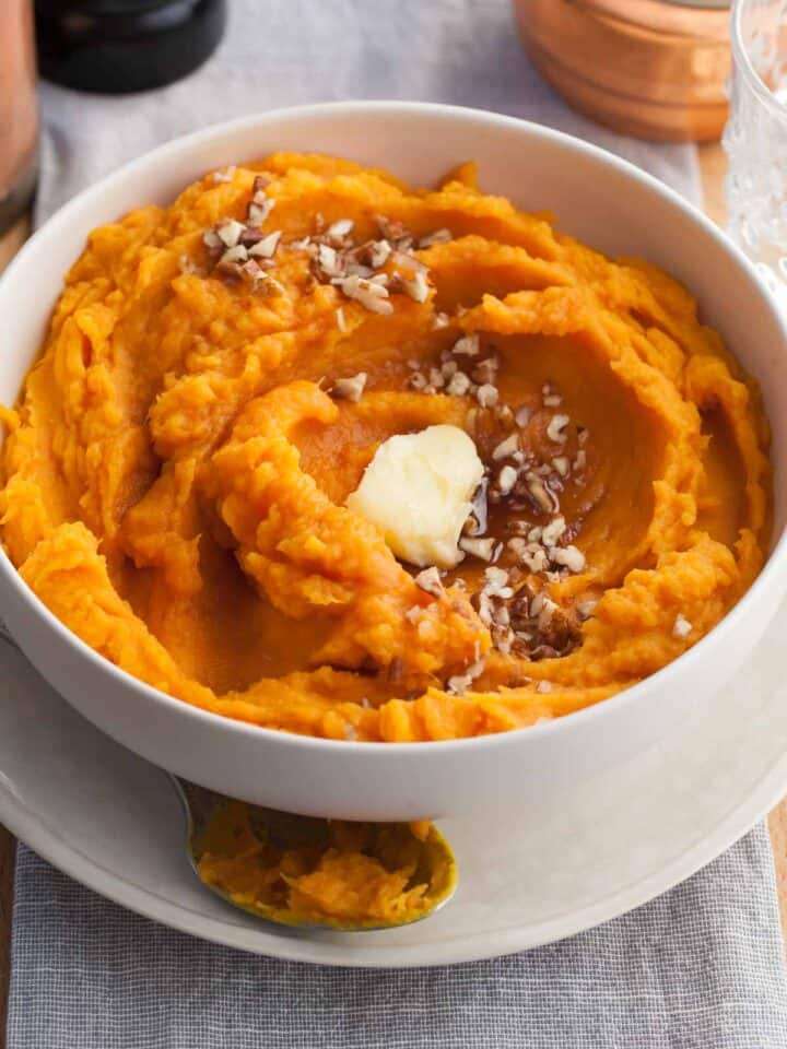 Steamed sweet potatoes mashed with vegan butter & maple syrup in serving bowl.