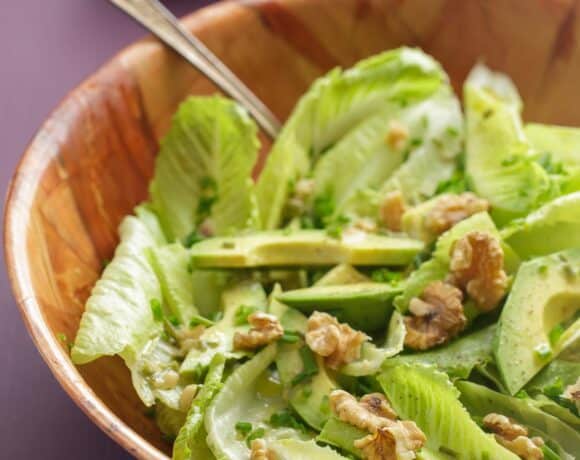 Fresh romaine lettuce and avocado salad with toasted walnuts and chives in a Dijon vinaigrette, served in a wood bowl.