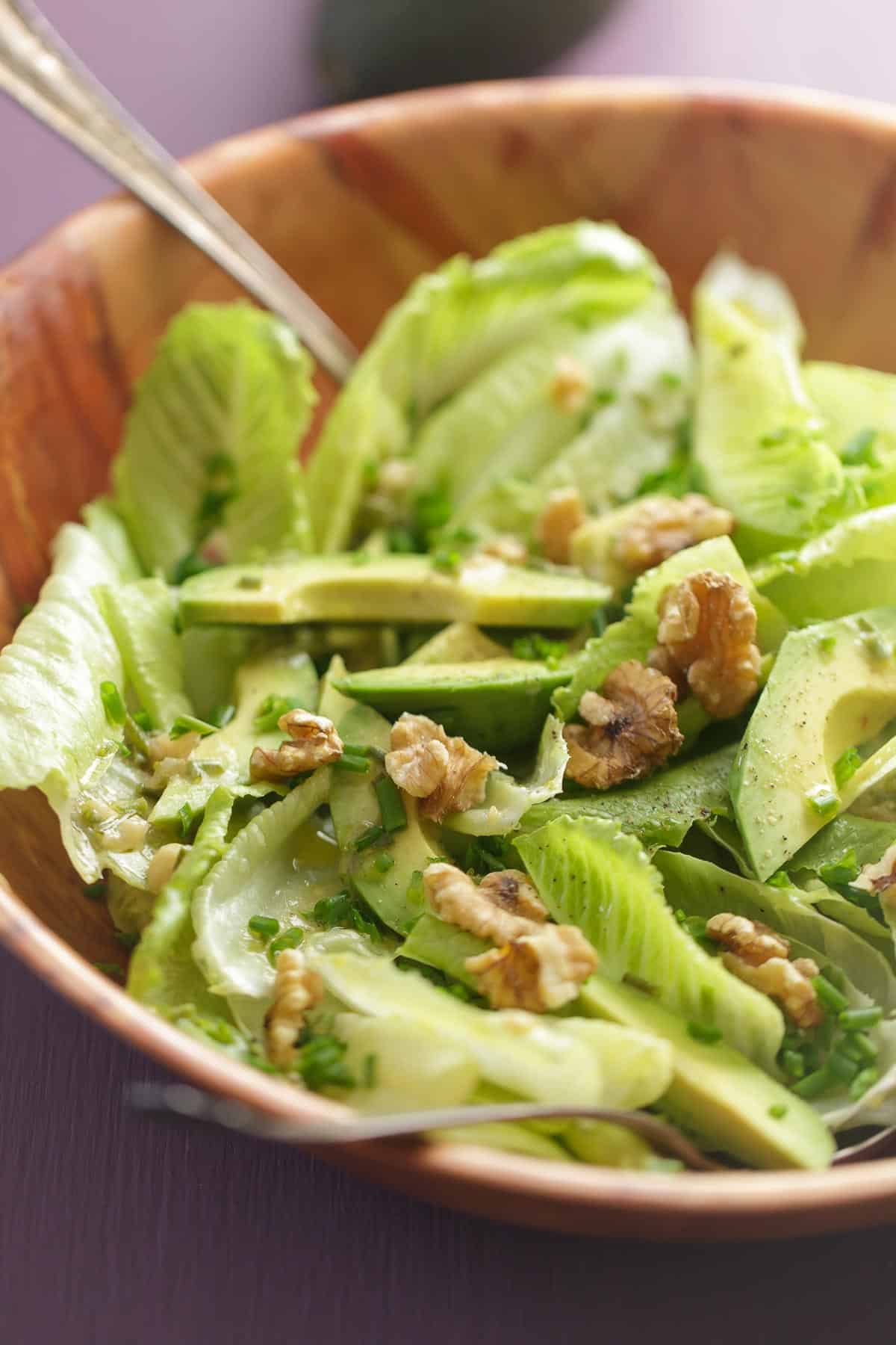 Romaine and avocado salad with walnuts and chives in a large bowl with Dijon vinaigrette