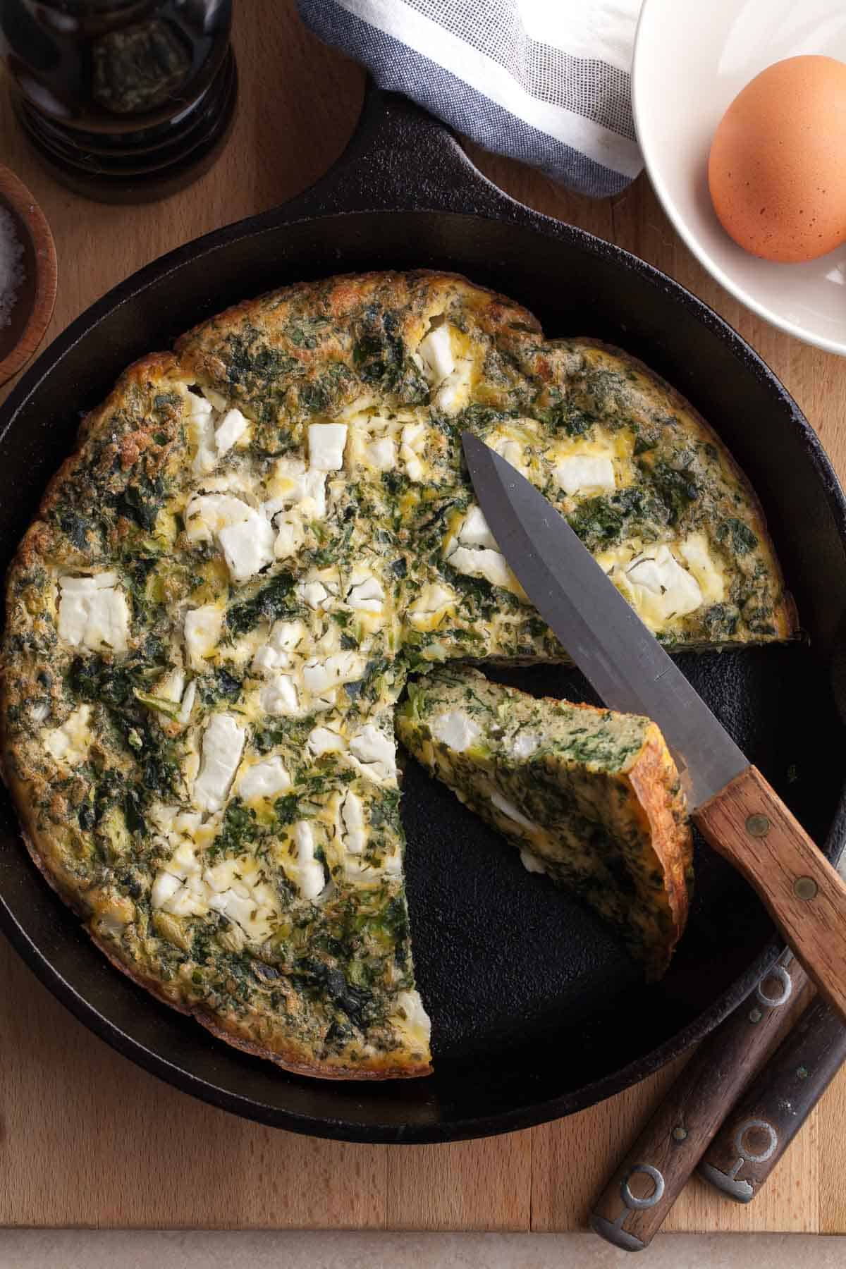 slice of spinach feta frittata in pan on side