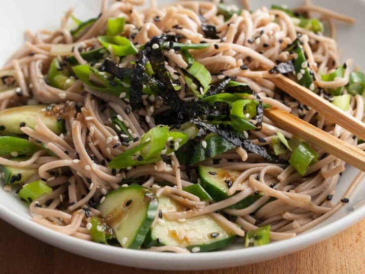 sesame soba noodles in bowl tossed in a sesame dressing and topped with scallions and sesame seeds