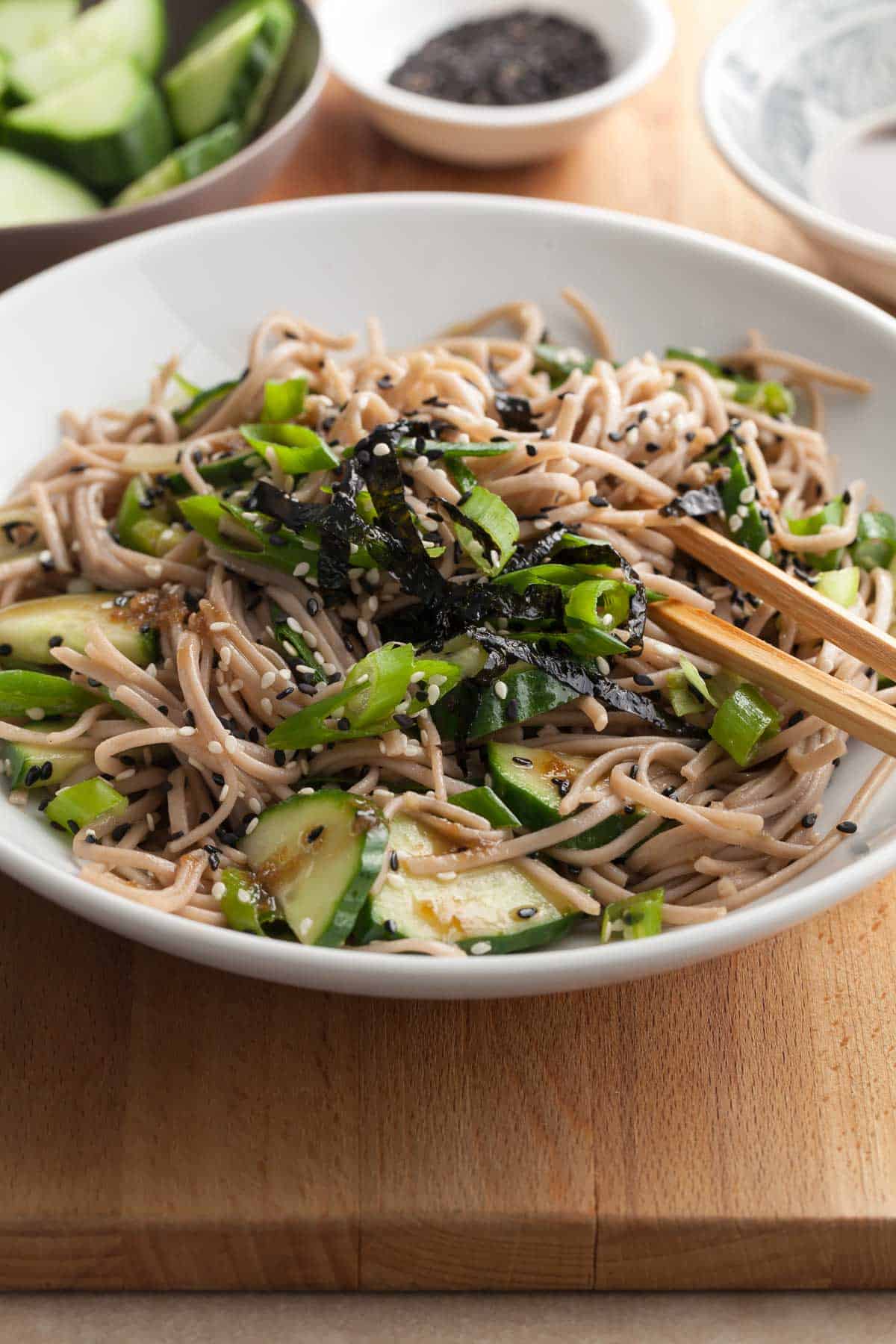 sesame soba noodles in bowl tossed in a sesame dressing and topped with scallions and sesame seeds
