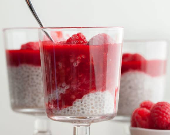 Raspberry Chia Seed Pudding in cup with raspberry sauce and spoon