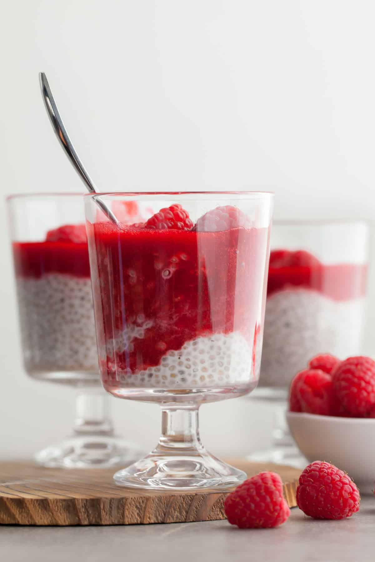 Raspberry Chia Seed Pudding in cup with raspberry sauce and spoon