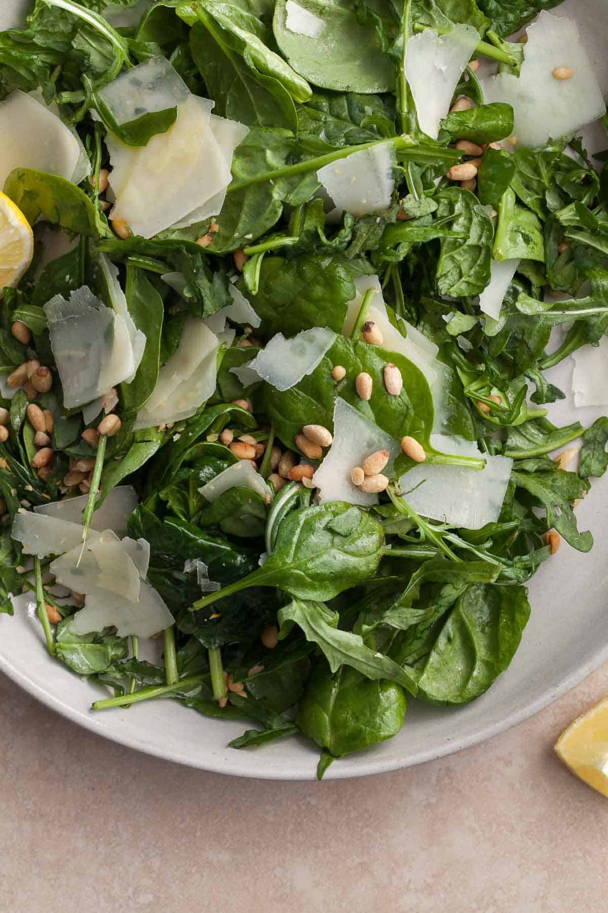 arugula and spinach salad with pecorino and pine nuts on plate 