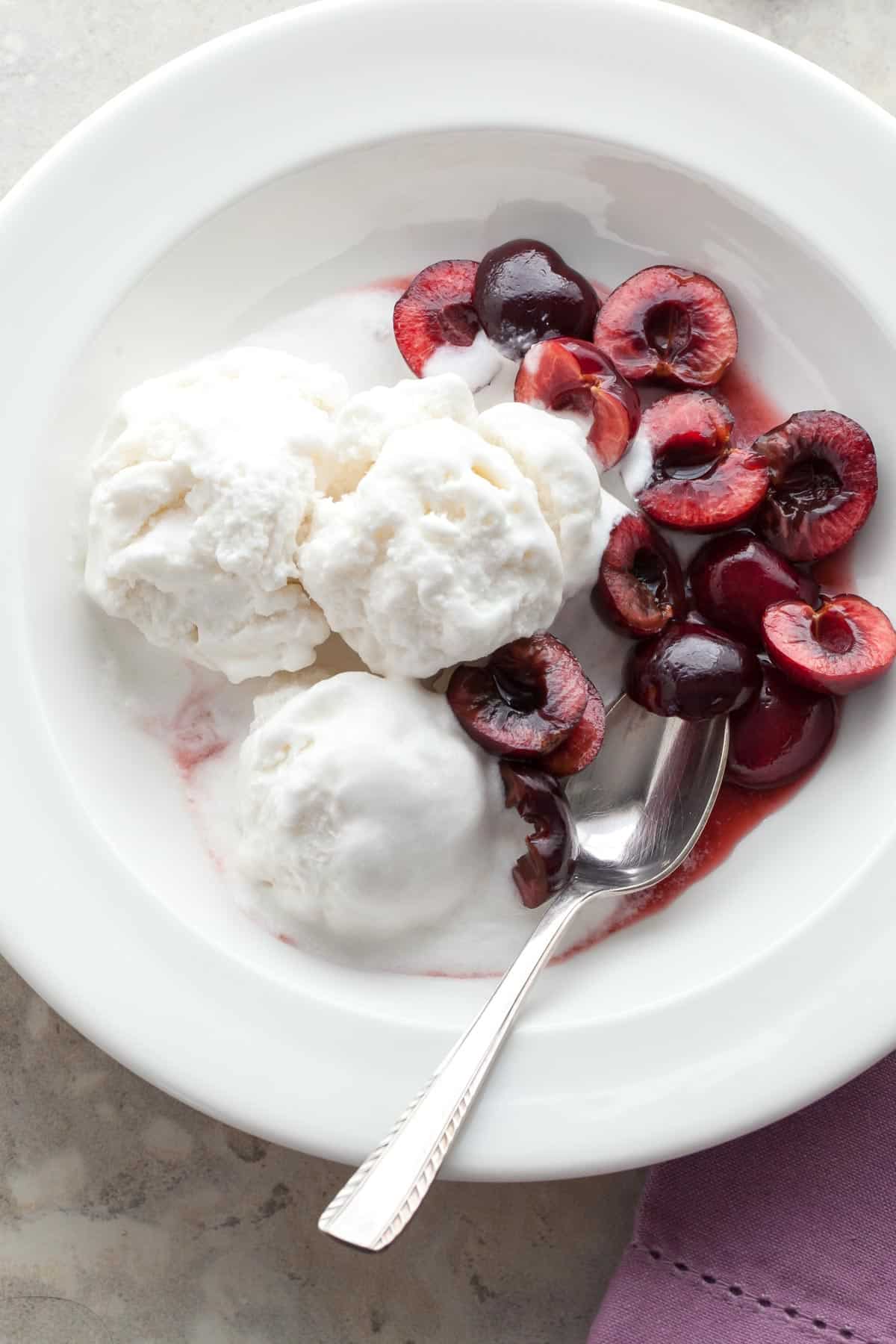 Coconut sorbet in a bowl made with coconut milk, coconut water, and shredded coconut topped served with cherries