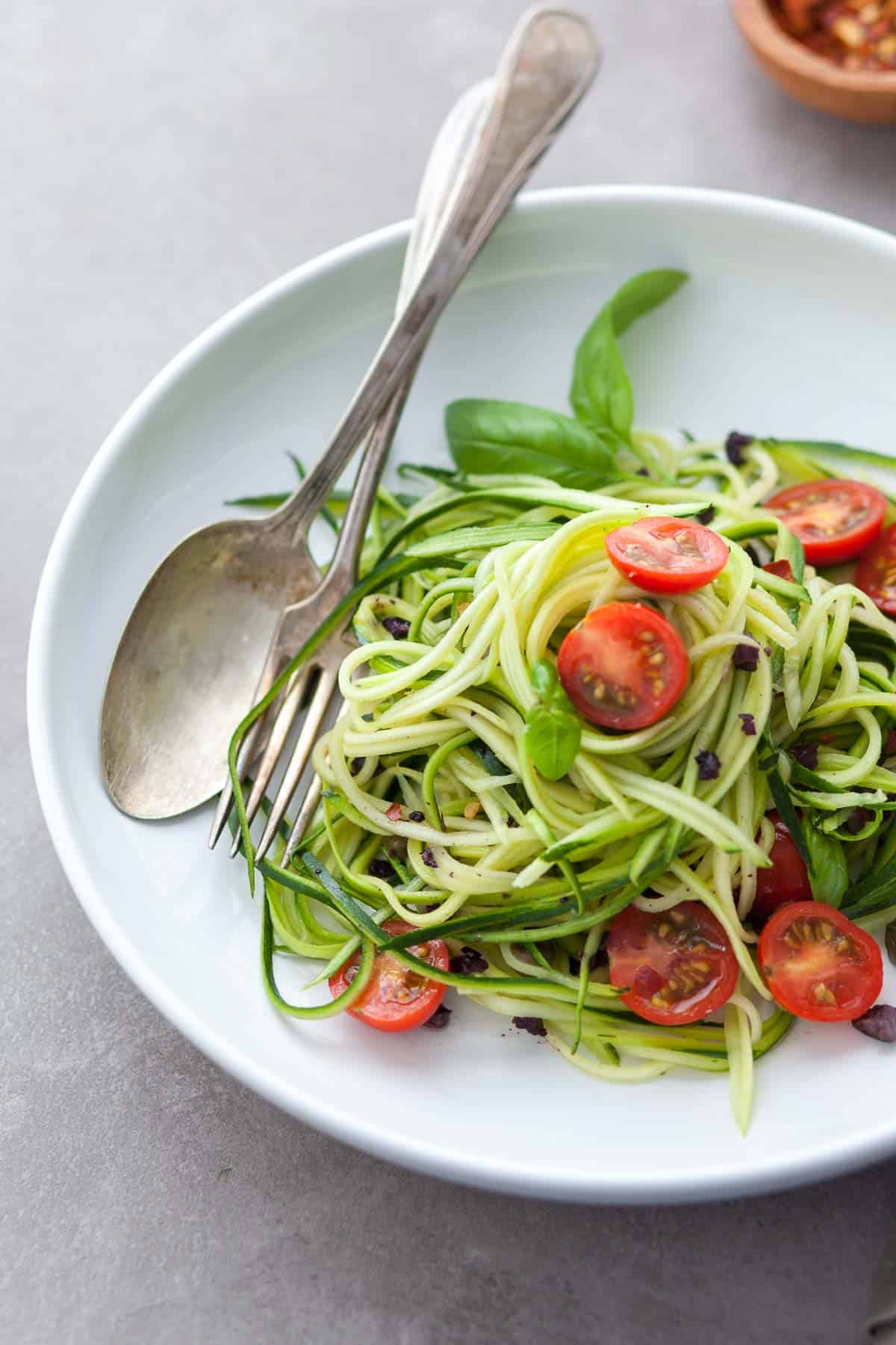 Mediterranean zucchini noodles with tomatoes, olives, capers, and basil on plate
