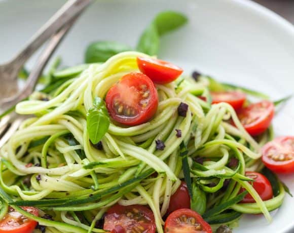 fresh and healthy no-cook summer zucchini noodles with cherry tomatoes on plate