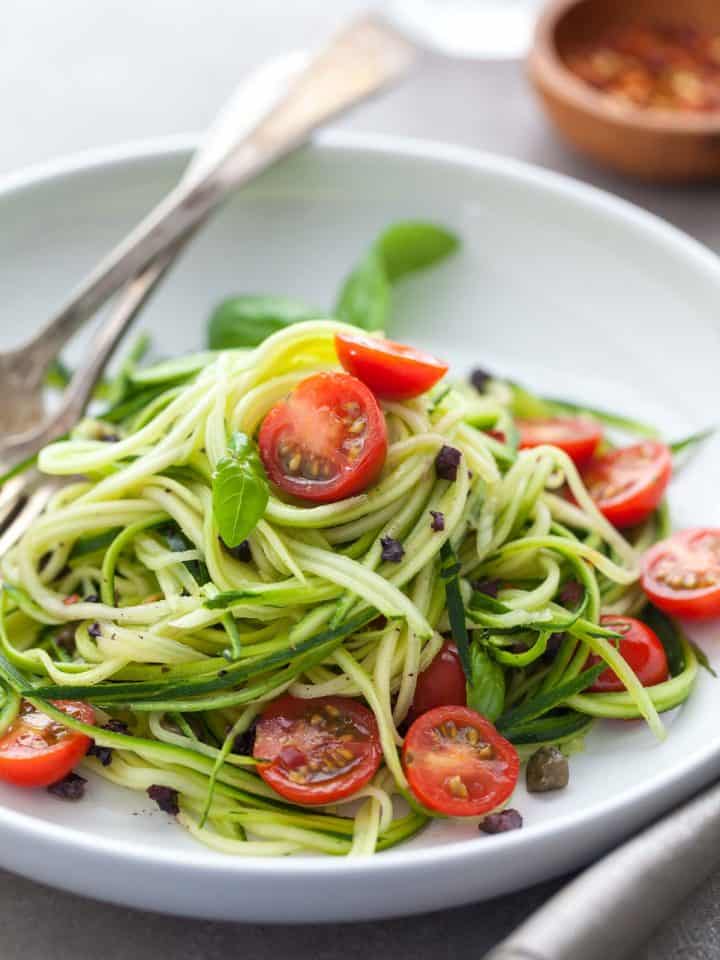 fresh and healthy no-cook summer zucchini noodles with cherry tomatoes on plate