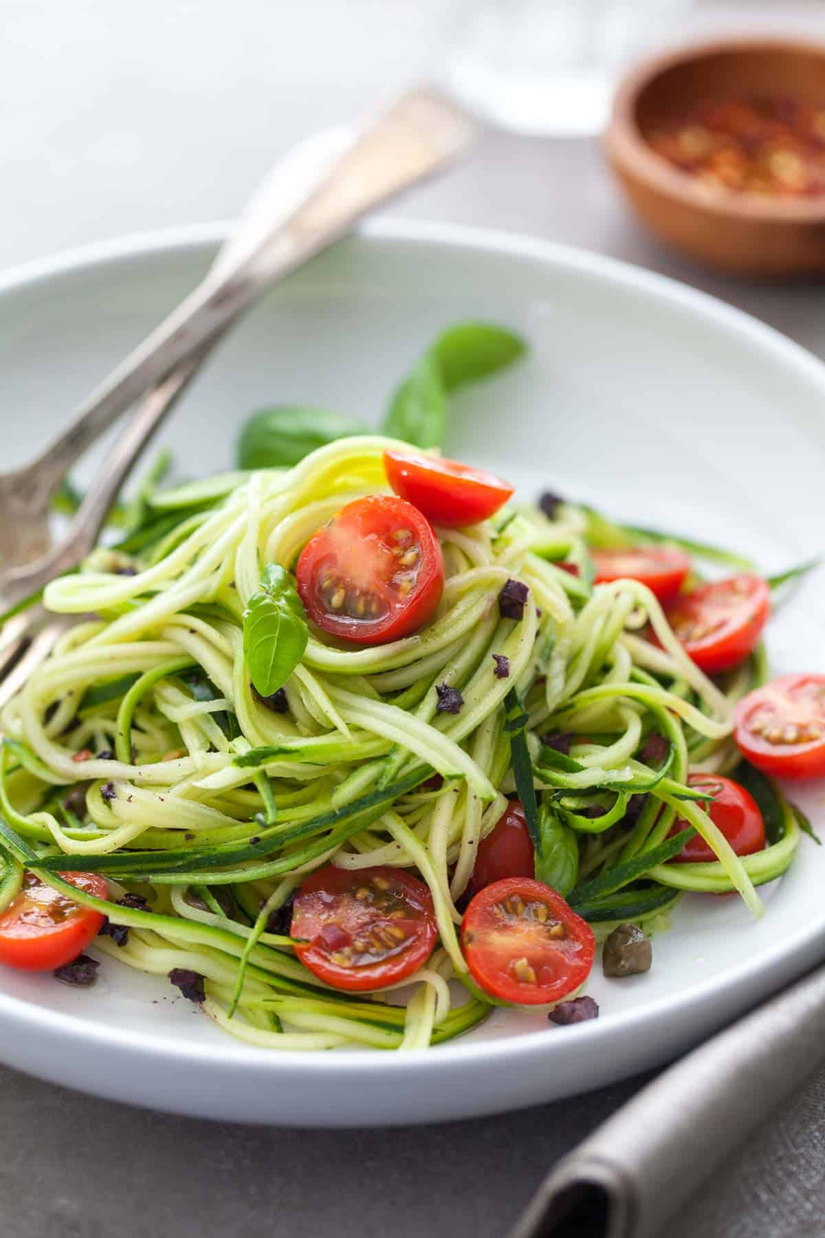 fresh and healthy no-cook summer zucchini noodles with cherry tomatoes on plate