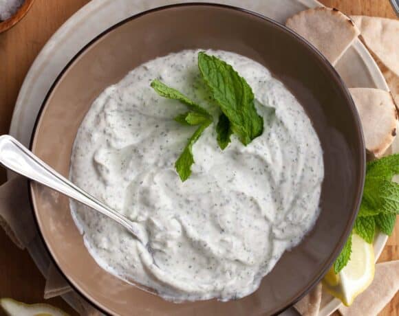 Top view of creamy yogurt mint sauce with fresh mint in bowl.
