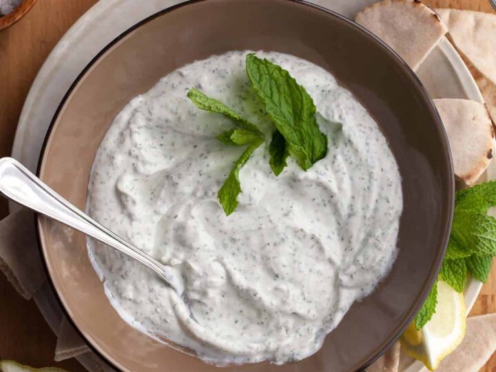 Top view of creamy yogurt mint sauce with fresh mint in bowl.