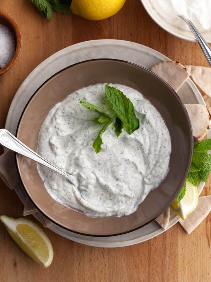 Top view of creamy yogurt mint sauce with fresh mint in bowl.