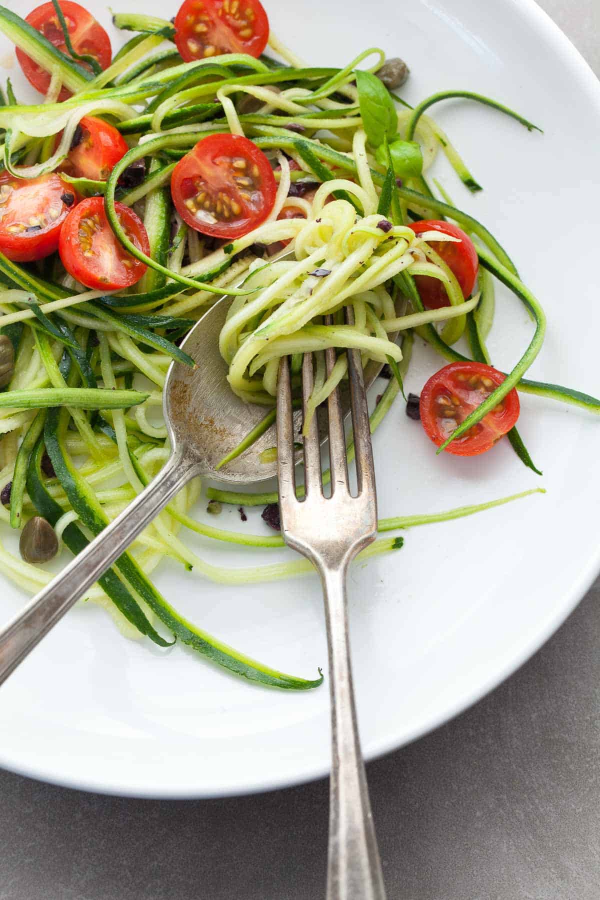 Mediterranean zoodles tossed with cherry tomatoes, olives, capers, basil, and lemon for an easy healthy dinner close up