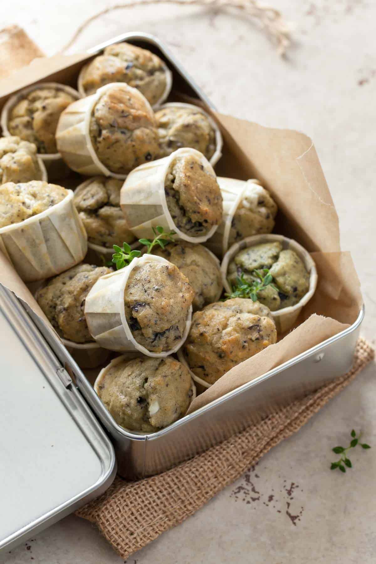 Soft Mediterranean-style gluten-free savory muffins made with feta, olives, and fresh herbs in box.