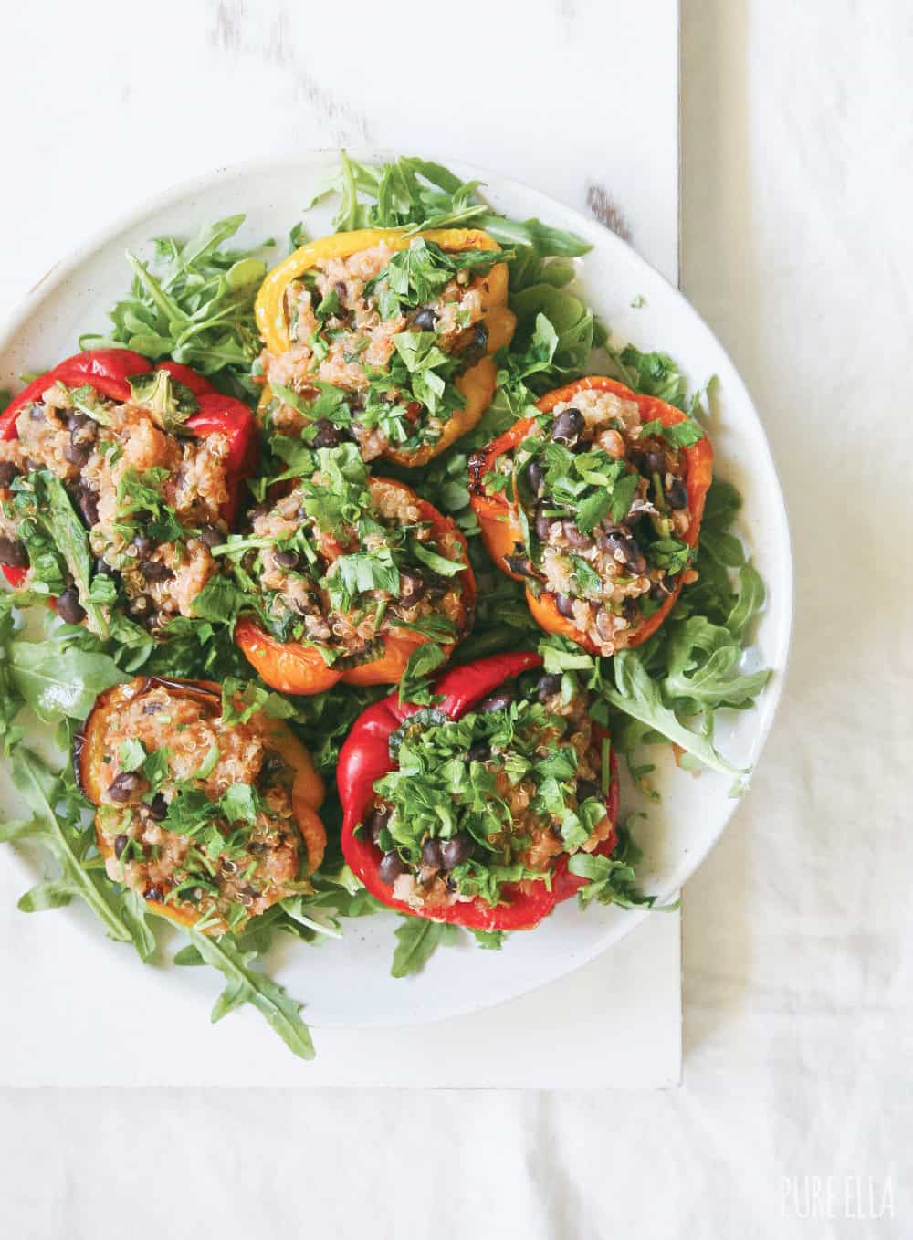 Top view of quinoa stuffed bell peppers arranged on a serving platter with fresh parsley garnish
