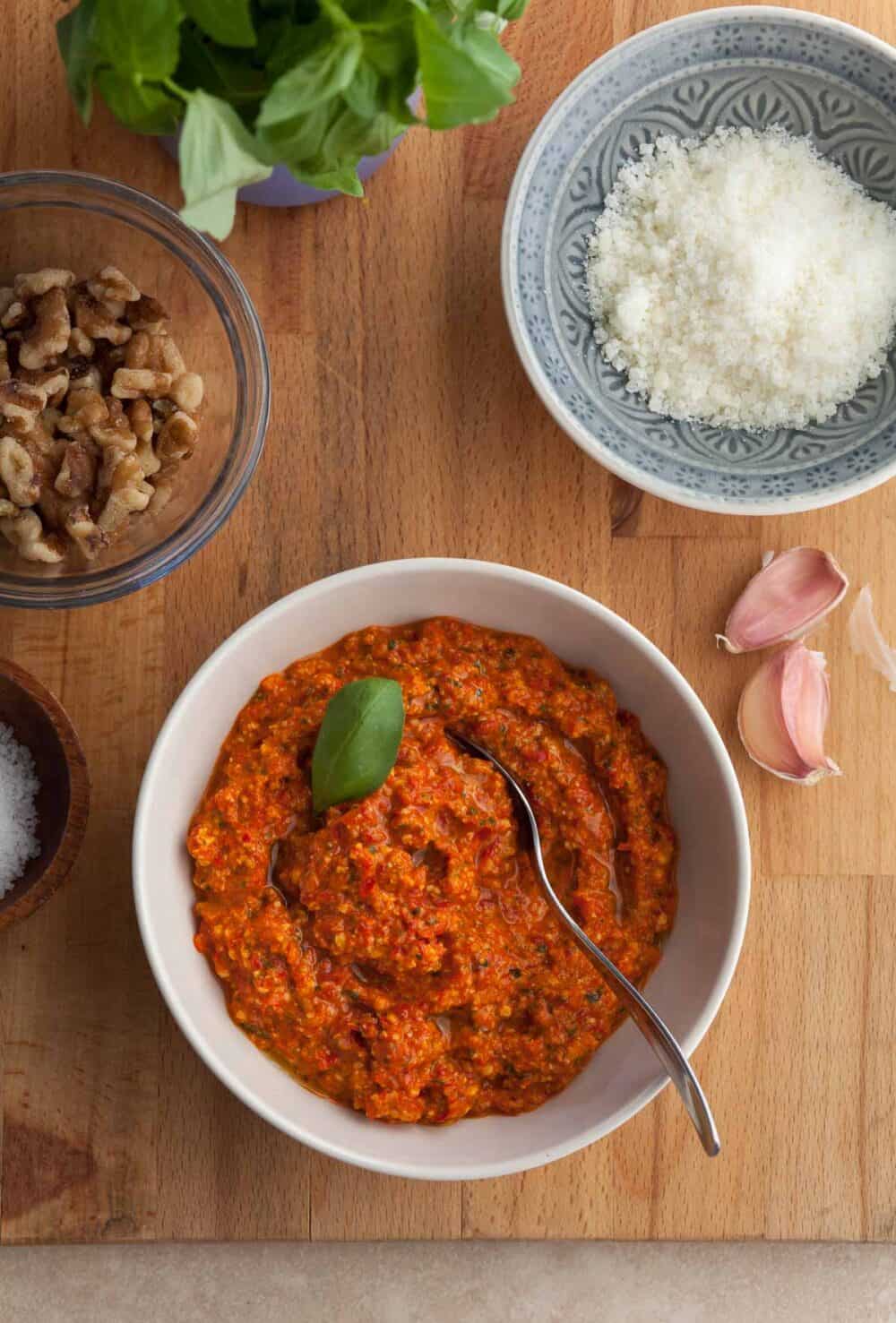 red pepper pesto made with jarred roasted peppers in a bowl topped with basil