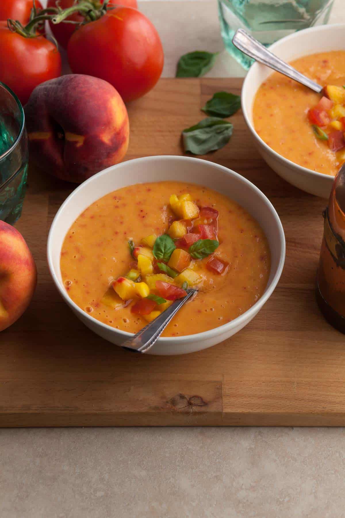 chilled peach soup served in bowls with chopped peaches and tomatoes