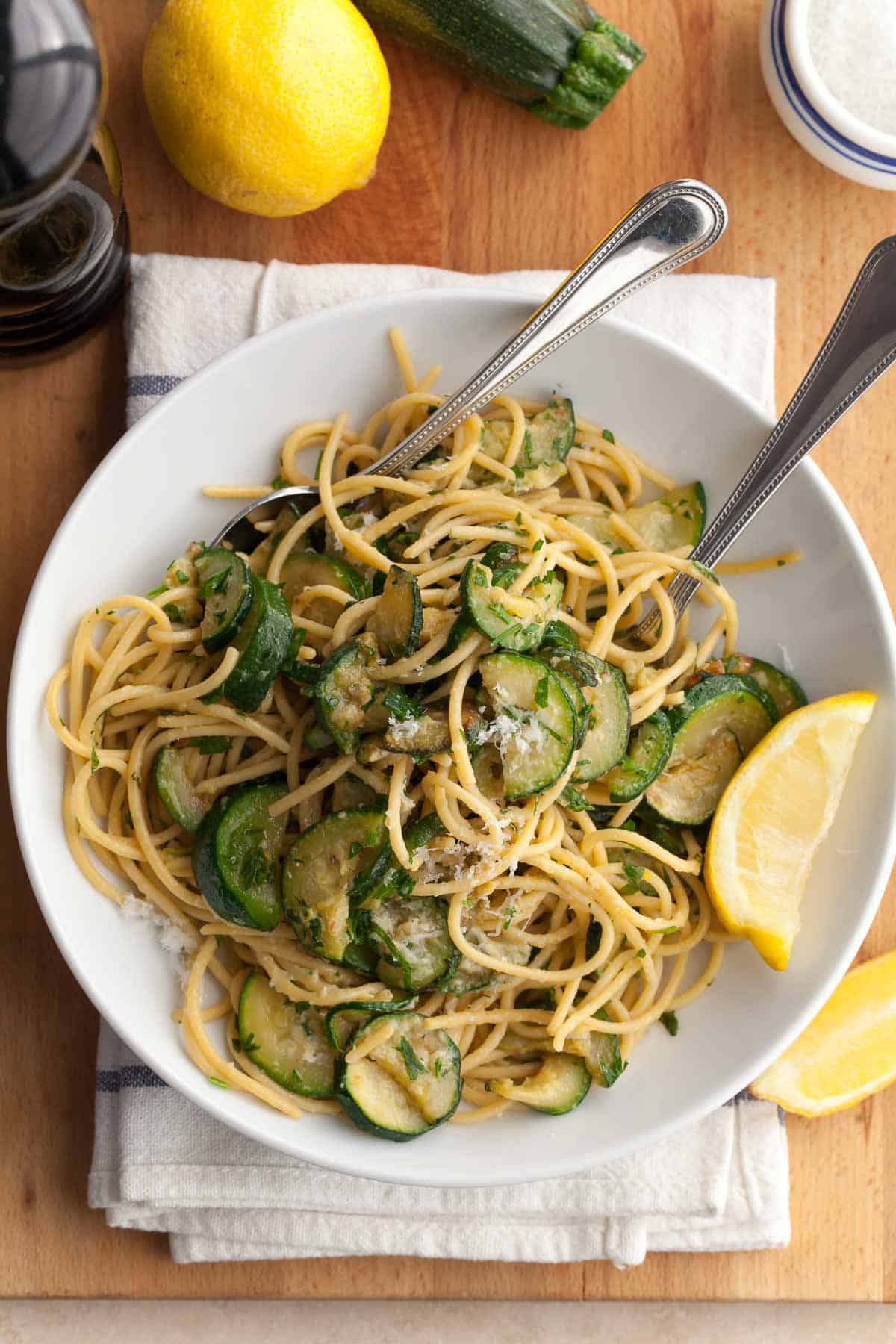 Zucchini pasta with lemon, herbs and cheese in white bowl