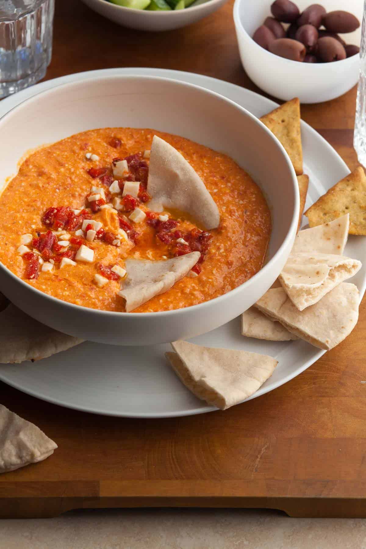 roasted red pepper feta dip in bowl with pita on plate