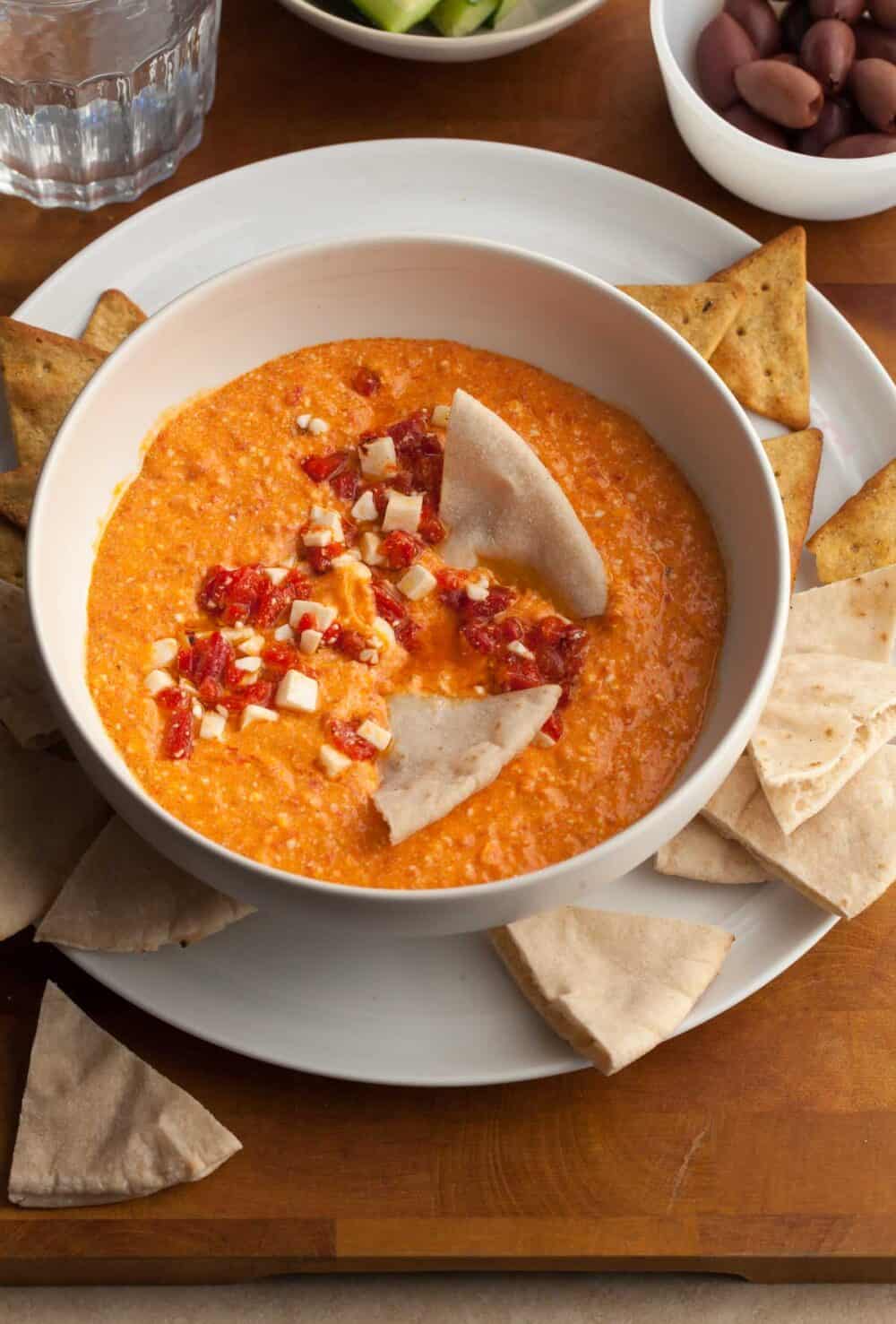 red pepper and feta dip in bowl served with pita and chips