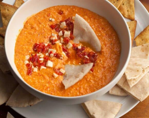 red pepper and feta dip in bowl served with pita and chips