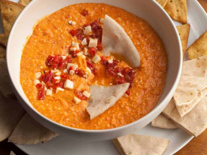 red pepper and feta dip in bowl served with pita and chips