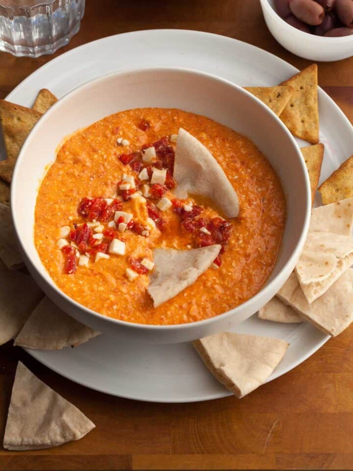 red pepper and feta dip in bowl served with pita and chips