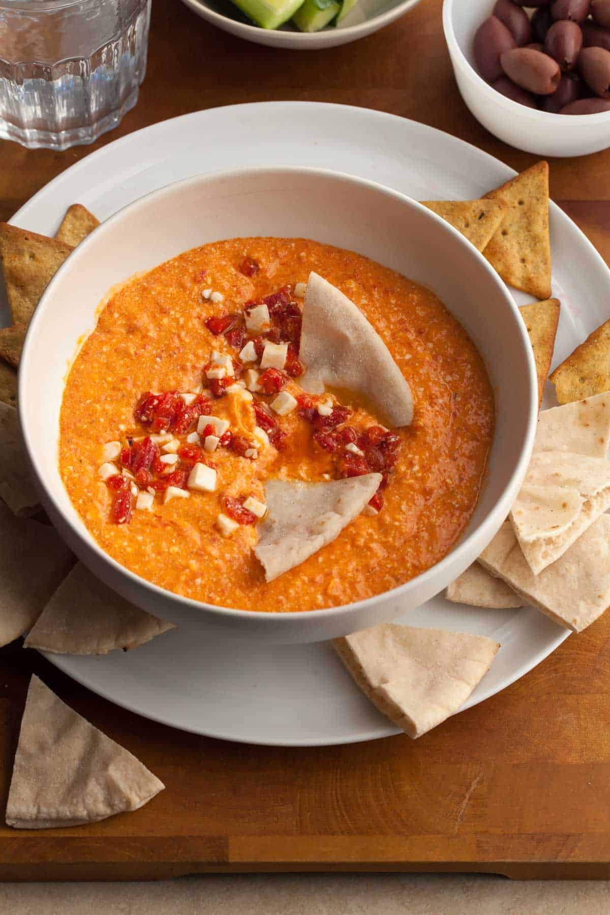 red pepper and feta dip in bowl served with pita and chips