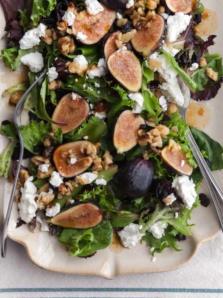 Fig and goat cheese salad with balsamic dressing, walnuts and cherries on serving platter