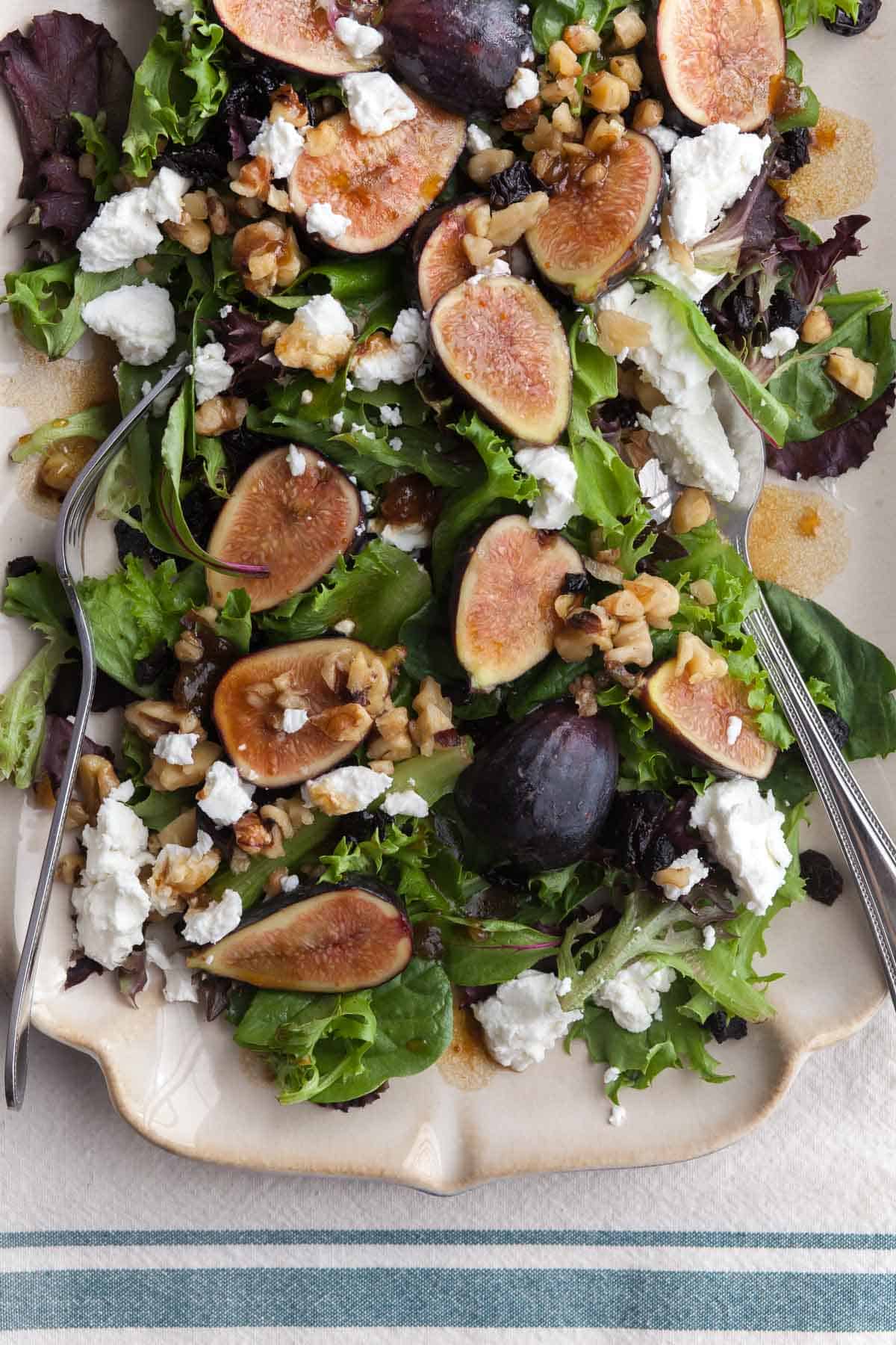 Fig and goat cheese salad with balsamic dressing, walnuts and cherries on serving platter