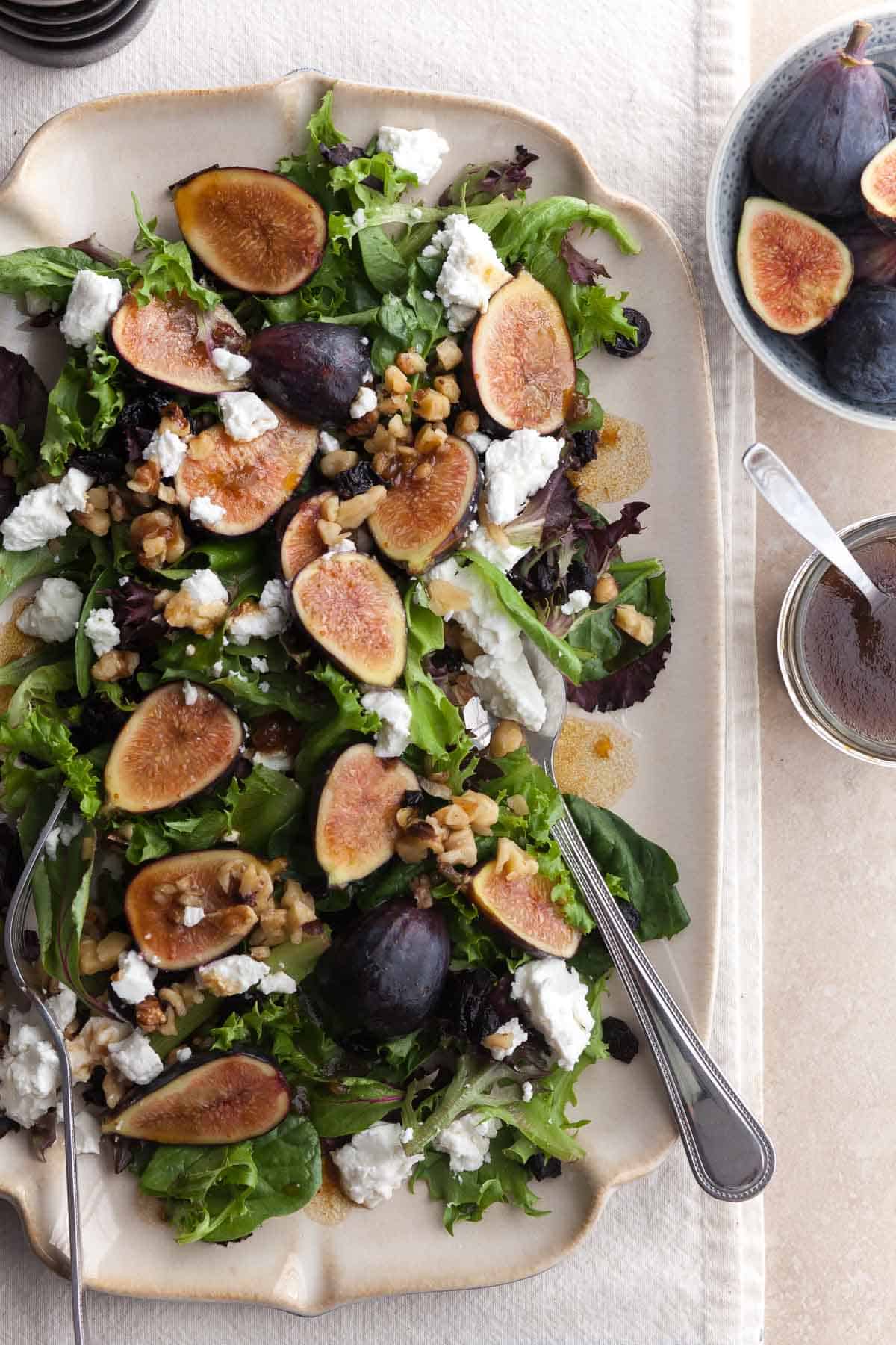 Fig and goat cheese salad on platter drizzled with balsamic vinaigrette and toasted walnuts