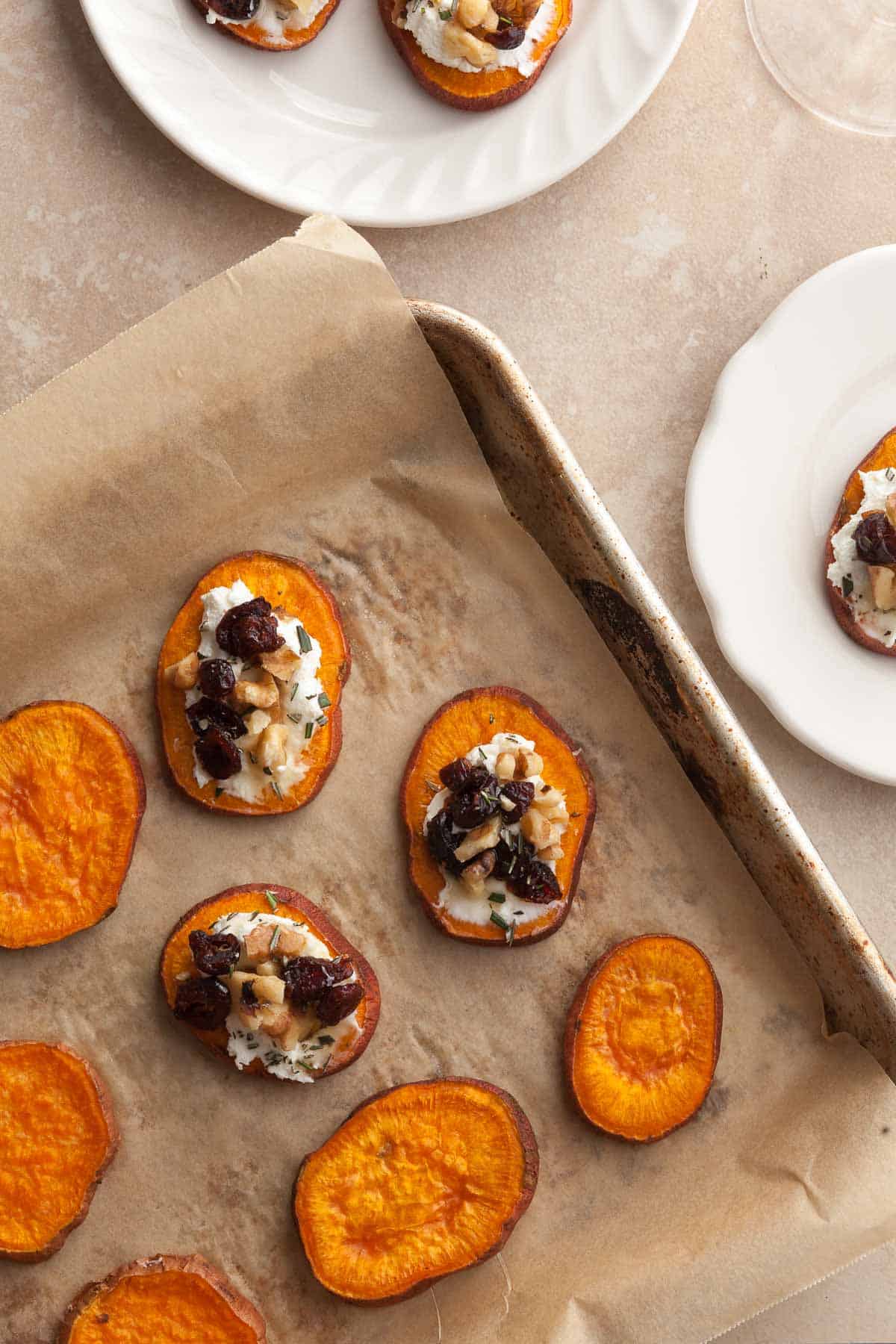 Sweet Potato Bites topped with Goat Cheese & Cranberries on sheet pan and plates
